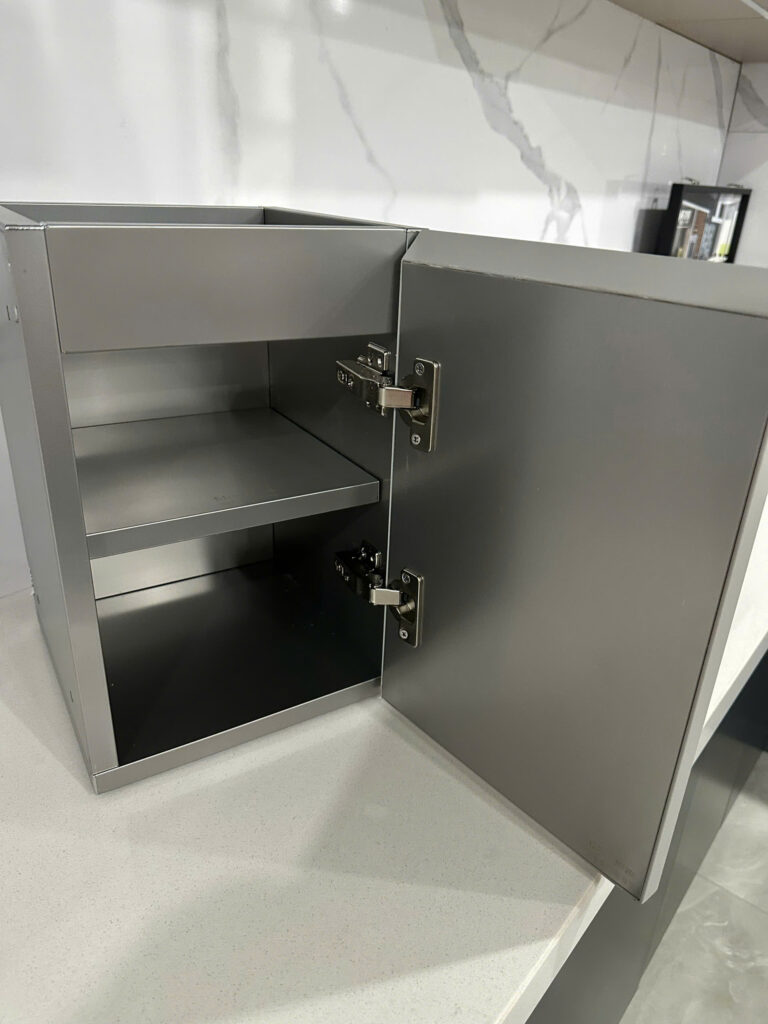 Xử lý tiếng ồn "cọc cạch" của tủ bếp inox bằng công nghệ hiện đại Tủ bếp Inox Module, Tủ bếp Inox FIND tu bep inox Ảnh chụp cận cảnh bản lề giảm chấn thủy lực cao cấp đang hoạt động